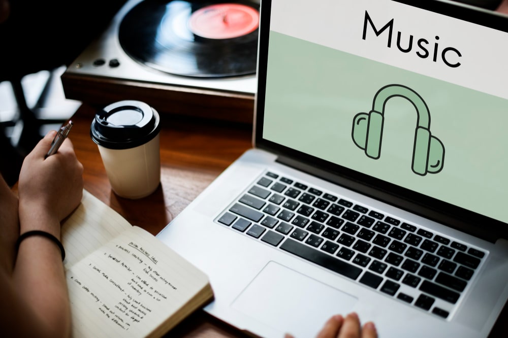 Personne prenant des notes avec ordinateur portable et utilisant musique libre de droit.