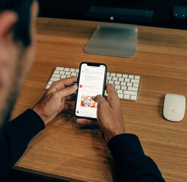 Personne utilisant un smartphone devant ordinateur.