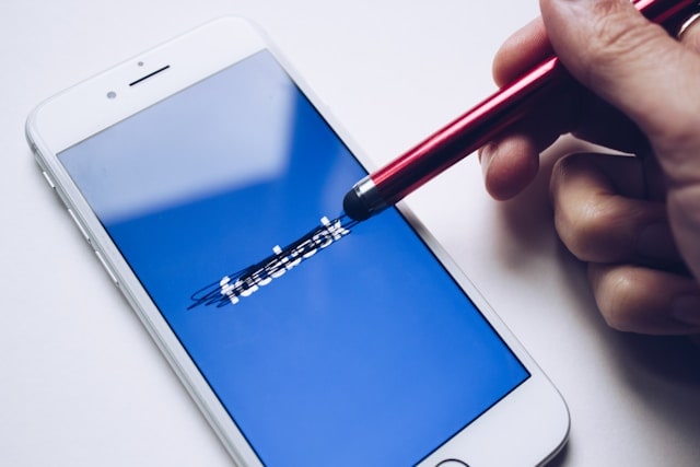 iPhone avec logo Facebook barré au stylet rouge.